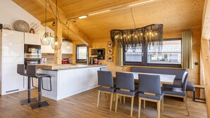 A modern kitchen with wooden accents, a central island, bar stools, and a dining area with benches. - Appealing chalet with sauna (Schladming - Pichl, Ennstal)