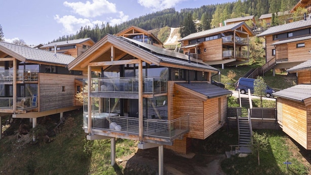 A cluster of wooden cabins with glass balconies, set against a mountainous backdrop. - Appealing chalet with sauna (Schladming - Pichl, Ennstal)