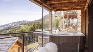 A wooden balcony with a hot tub, large windows, and a view of mountains. - Appealing chalet with sauna (Schladming - Pichl, Ennstal)