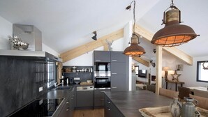 Una cocina moderna con una isla central, electrodomésticos de acero inoxidable y vigas de madera rústica.
