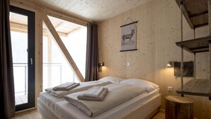 Una habitación de madera con una cama, un estante de cuerda colgante y un cuadro de un animal en la pared.