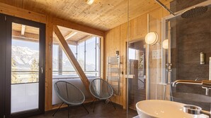 Un intérieur en bois avec une grande fenêtre, une douche en verre et un lavabo blanc.