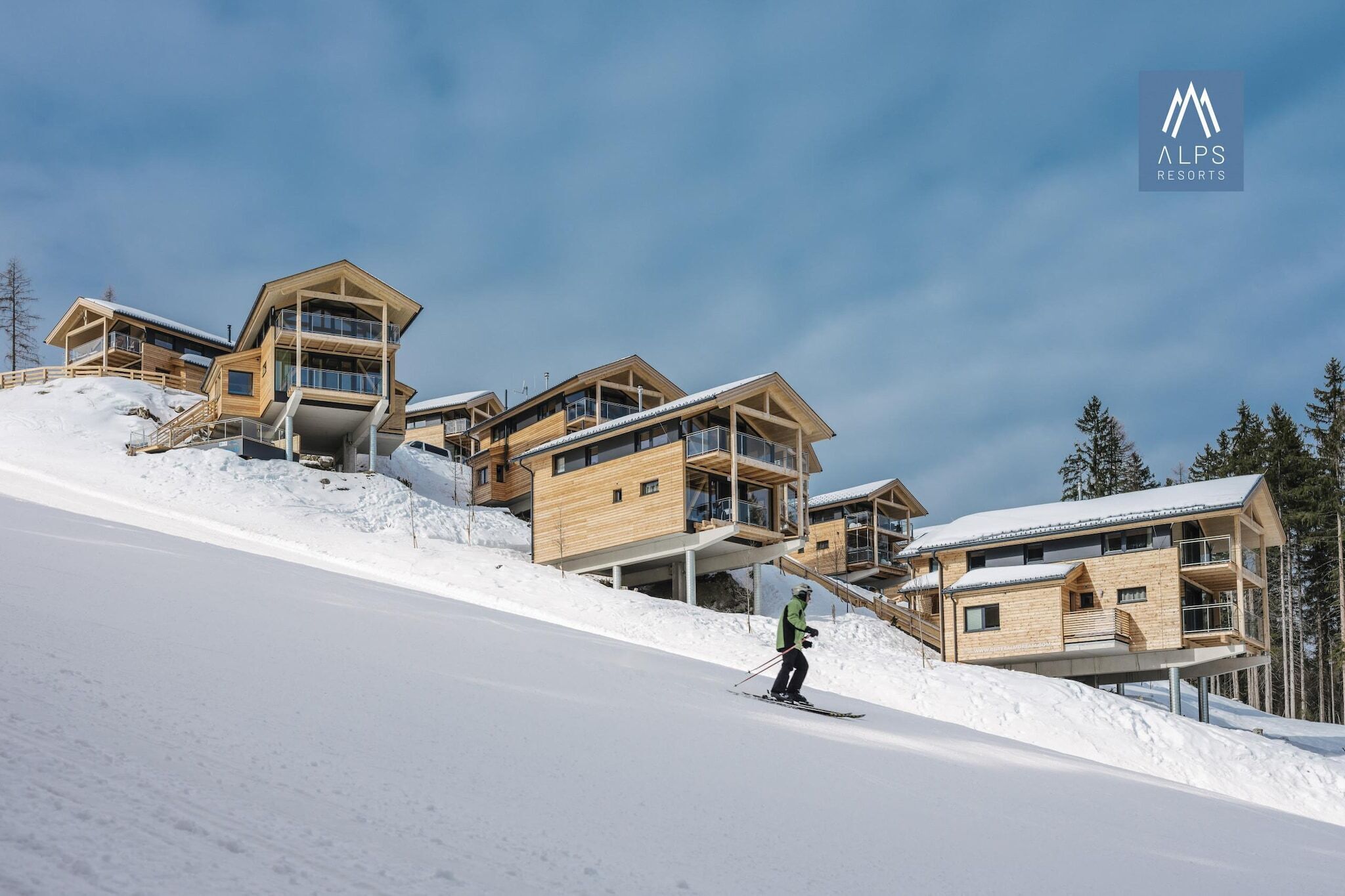 Un moderno complejo de esquí con cabañas de madera en una ladera nevada.