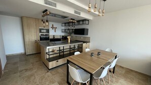 Una cocina moderna con una isla central, sillas blancas y una mesa de comedor de madera.