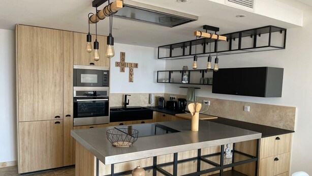 Una cocina moderna con una isla central, horno empotrado y armarios negros.