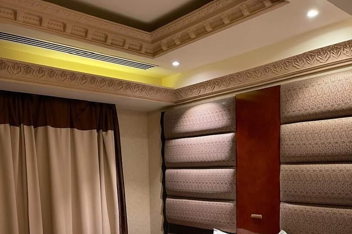 Ein Hotelzimmer mit einem großen Bett, einem Nachttisch aus Holz und einem Kopfteil mit strukturierter Musterung.