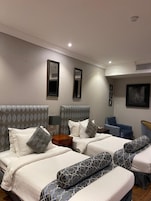 Habitación de hotel con dos camas, un escritorio, una silla y un ventanal grande.