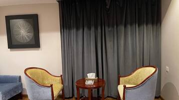 A room with two armchairs, a small round table with a tissue box, and a framed abstract artwork on the wall.