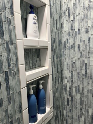 Un estante de baño con loción Dove y protectores solares Aveeno.