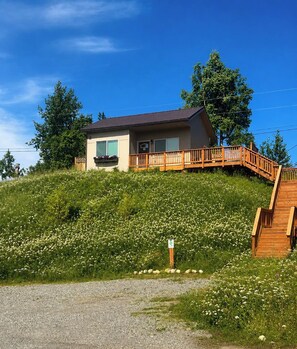 Ein zweistöckiges Gebäude mit einer Holzterrasse und einer Treppe, die zu der oberen Etage führt.