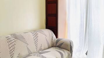 A living room with a sofa, a wooden cabinet, and a window with curtains.
