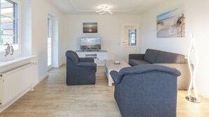 A modern living room with grey sofas, a coffee table, and artwork on the walls. - Ferienwohnung Schöne Aussicht in Emmelsbüll-horsbüll (Emmelsbüll-Horsbüll)