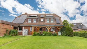 A two-story house with a brick facade, a pitched roof, and solar panels on the roof.
