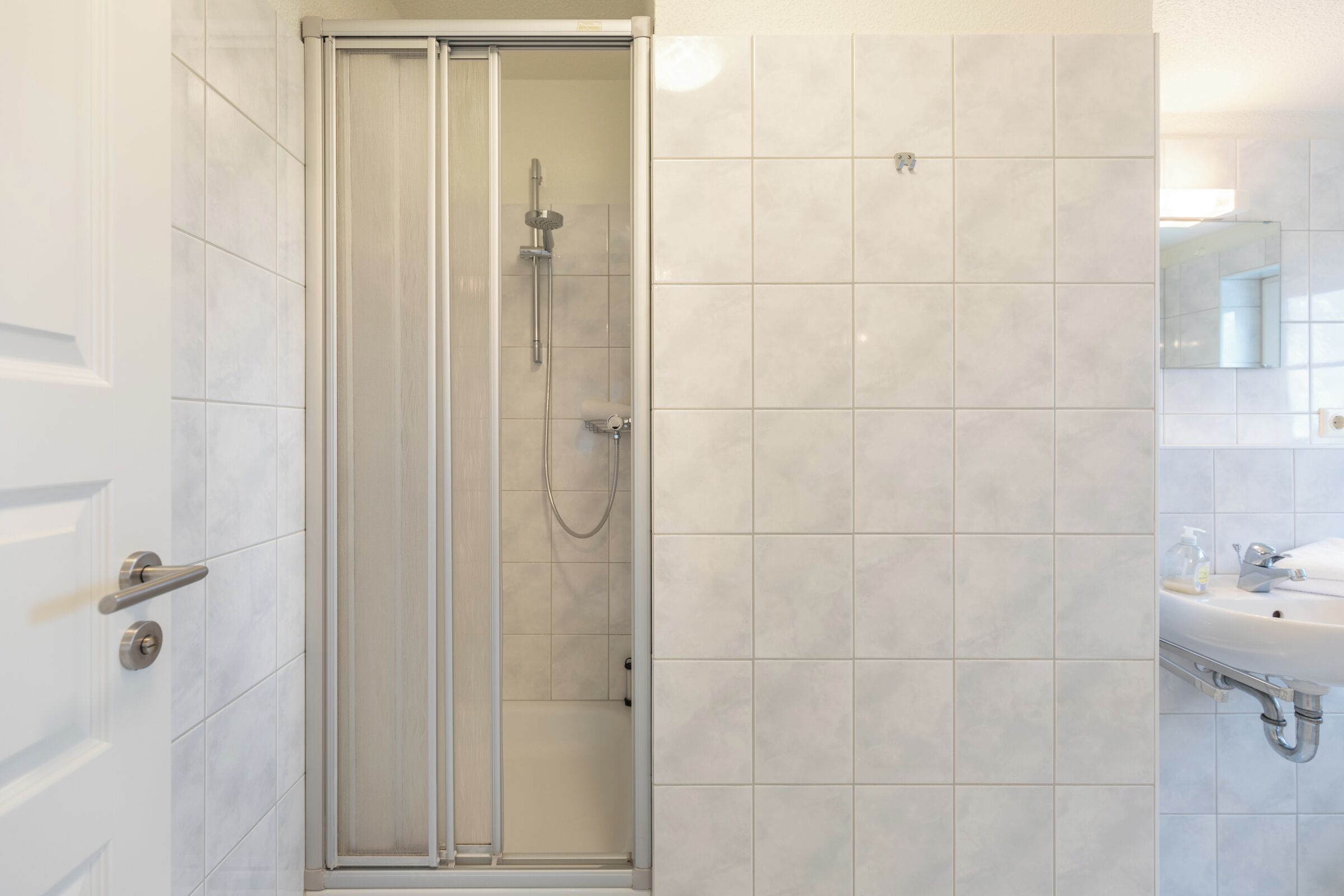 A modern bathroom with a glass-enclosed shower, a sink, and a mirror.