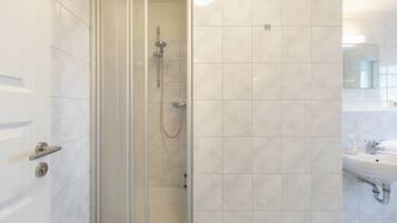 A modern bathroom with a glass-enclosed shower, a sink, and a mirror.