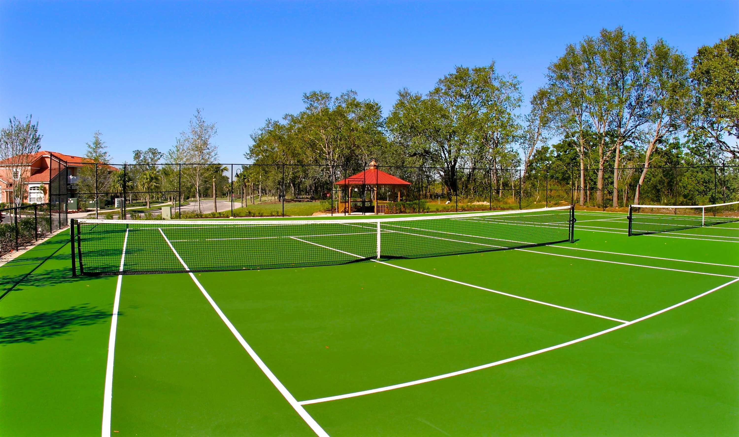 Un court de tennis avec un kiosque et des arbres en arrière-plan.