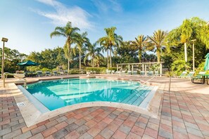 A swimming pool with lounge chairs and umbrellas, surrounded by palm trees. - Emerald Paradise. New decor, 15 mins from Disney! (Kissimmee)