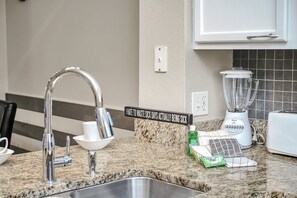 A kitchen with a granite countertop, a stainless steel sink, a white toaster, and a blender. - Family Townhouse near Disney (Kissimmee)