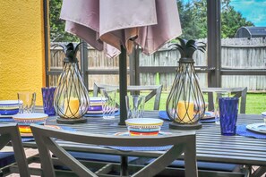 An outdoor dining area with metal tables, chairs, and a covered section with a tablecloth. - Family Townhouse near Disney (Kissimmee)