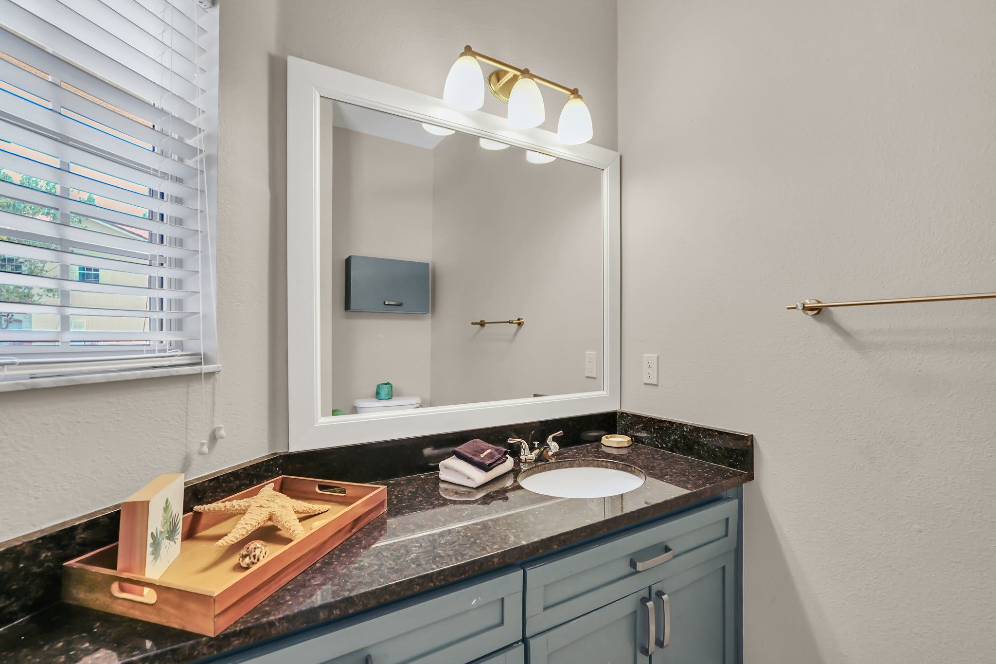 Une salle de bain avec un grand miroir, un lavabo et un meuble-lavabo doté de tiroirs.