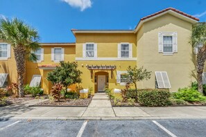 A yellow building with a central entrance, white shutters, and a tiled roof. - Family Townhouse near Disney (Kissimmee)