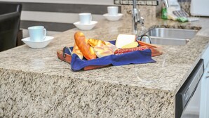 Un plan de travail de cuisine avec un plateau de pains et de viennoiseries, un grille-pain et un évier.