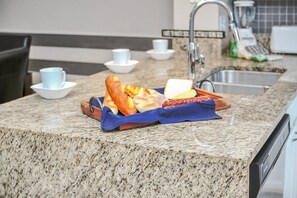 A kitchen counter with a tray of bread and pastries, a toaster, and a sink. - Family Townhouse near Disney (Kissimmee)