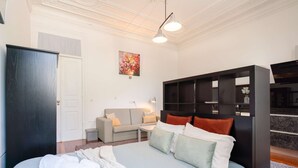 A modern hotel room with a bed, a sofa, a desk, and a bookshelf. - Cozy Studio in Central Porto: A/C and Kitchen (Porto)