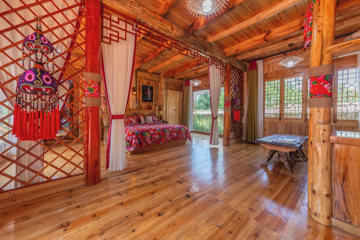Una habitación rústica de madera con una cama, una mesa y un tapiz decorativo.