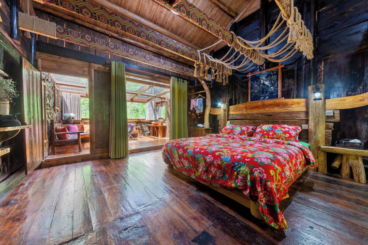 Una habitación de madera con una cama, un banco y una mesa.