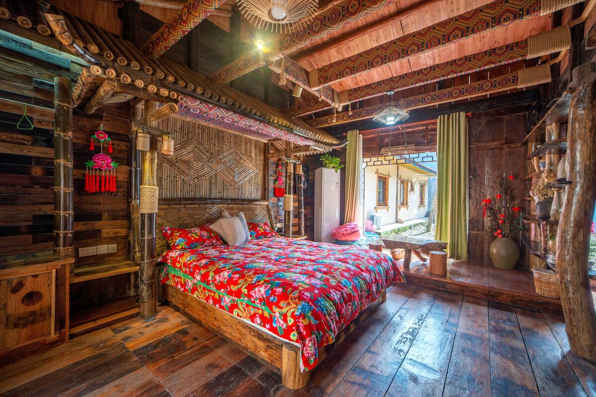 Una habitación de madera con una cama, un banco de madera y una pequeña mesa.
