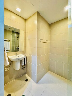 A bathroom with a sink, mirror, and shower. - Hubomoto Megaworld Suites (Iloilo)