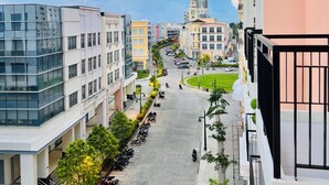 A modern urban street with multi-story buildings, a clear sky, and a central green space. - Hubomoto Megaworld Suites (Iloilo)