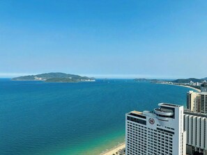 A coastal cityscape with a view of the sea, buildings, and a distant island.