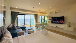 Une chambre d’hôtel moderne dotée d’un grand lit, d’un canapé, d’un coin repas et d’un téléviseur permettant d’accéder à des services de diffusion en continu.