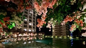 Une piscine extérieure dotée d’un sol carrelé, entourée d’une végétation luxuriante et de plantes en fleurs.