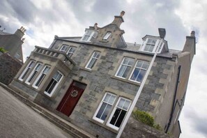 A stone building with a red door, multiple windows, and a chimney. - Formerly the Crannoch Hotel, this wonderful property can sleep up to 18
 (Cullen)