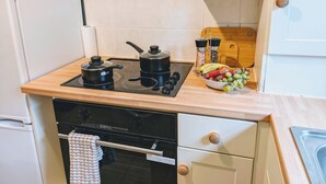 Une petite cuisine équipée d’une cuisinière, d’un four et d’un saladier rempli de fruits posé sur le plan de travail.