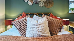 Un lit avec plusieurs oreillers et un mur décoré de divers objets tissés.