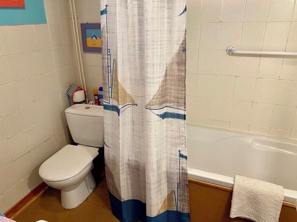 Une salle de bain équipée de toilettes, d’une baignoire et d’un rideau de douche.