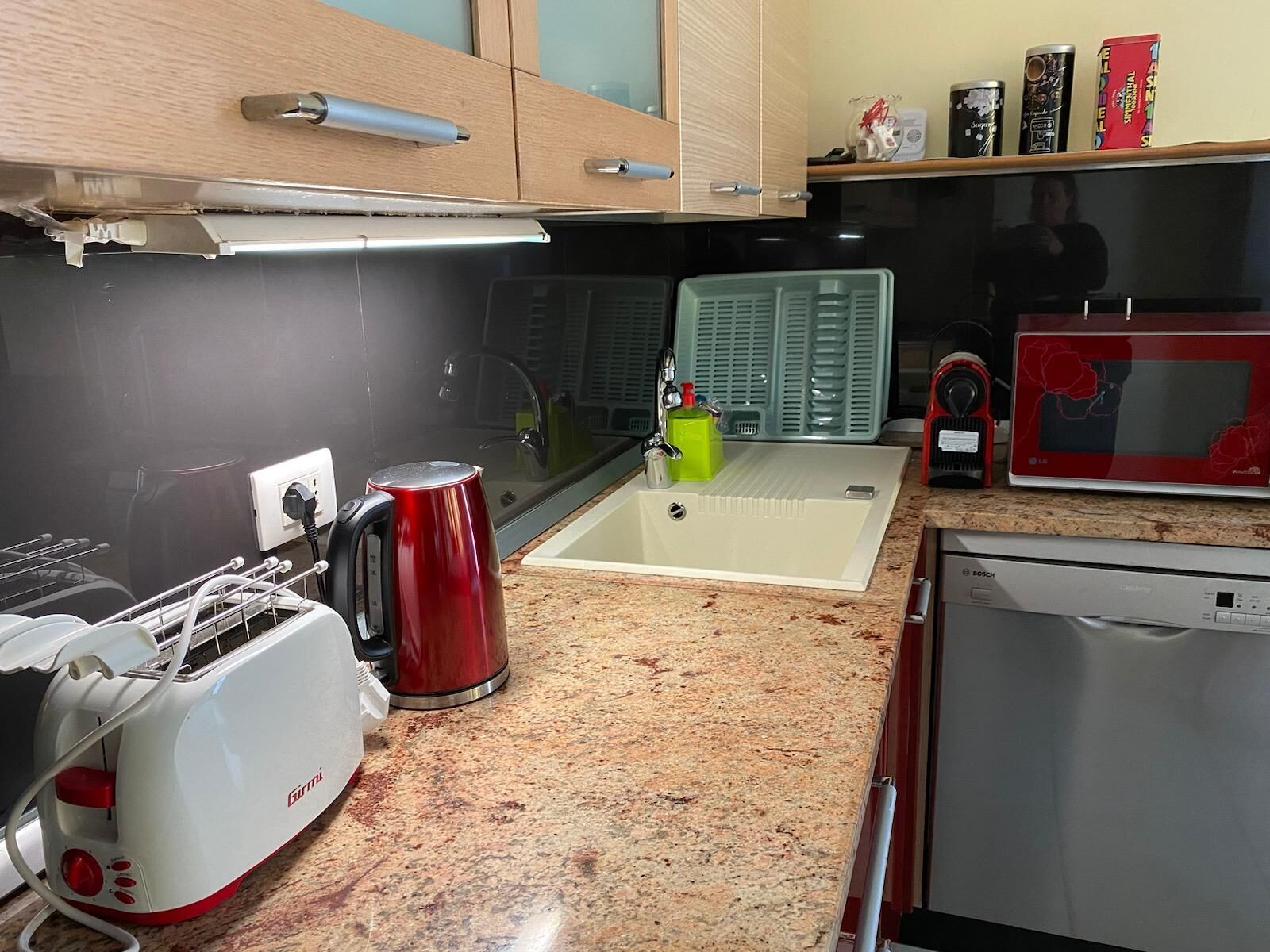 A kitchen with a sink, a toaster, a kettle, and a microwave.