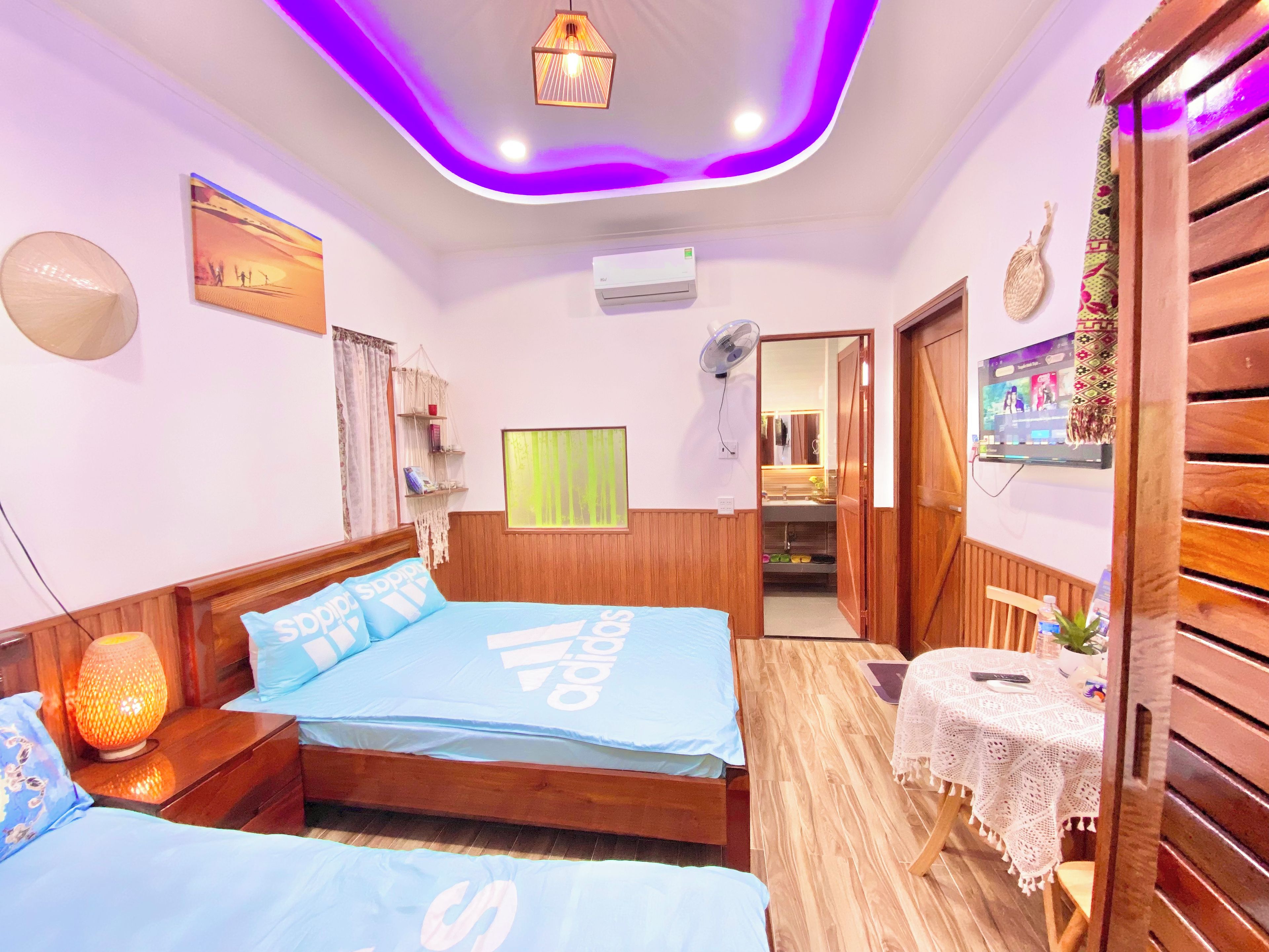 A hotel room with a bed, bedside table, lamp, and a small table with a tablecloth.