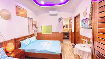 A hotel room with a bed, bedside table, lamp, and a small table with a tablecloth.