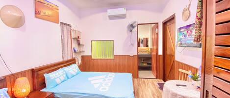 A hotel room with a bed, bedside table, lamp, and a small table with a tablecloth.