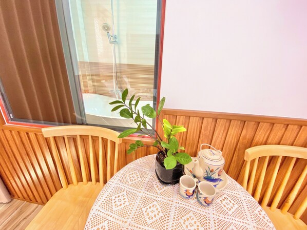 A wooden chair and table with a lace tablecloth, a potted plant, and a tea set. - Sea-breeze homestay (Phu Thuy)