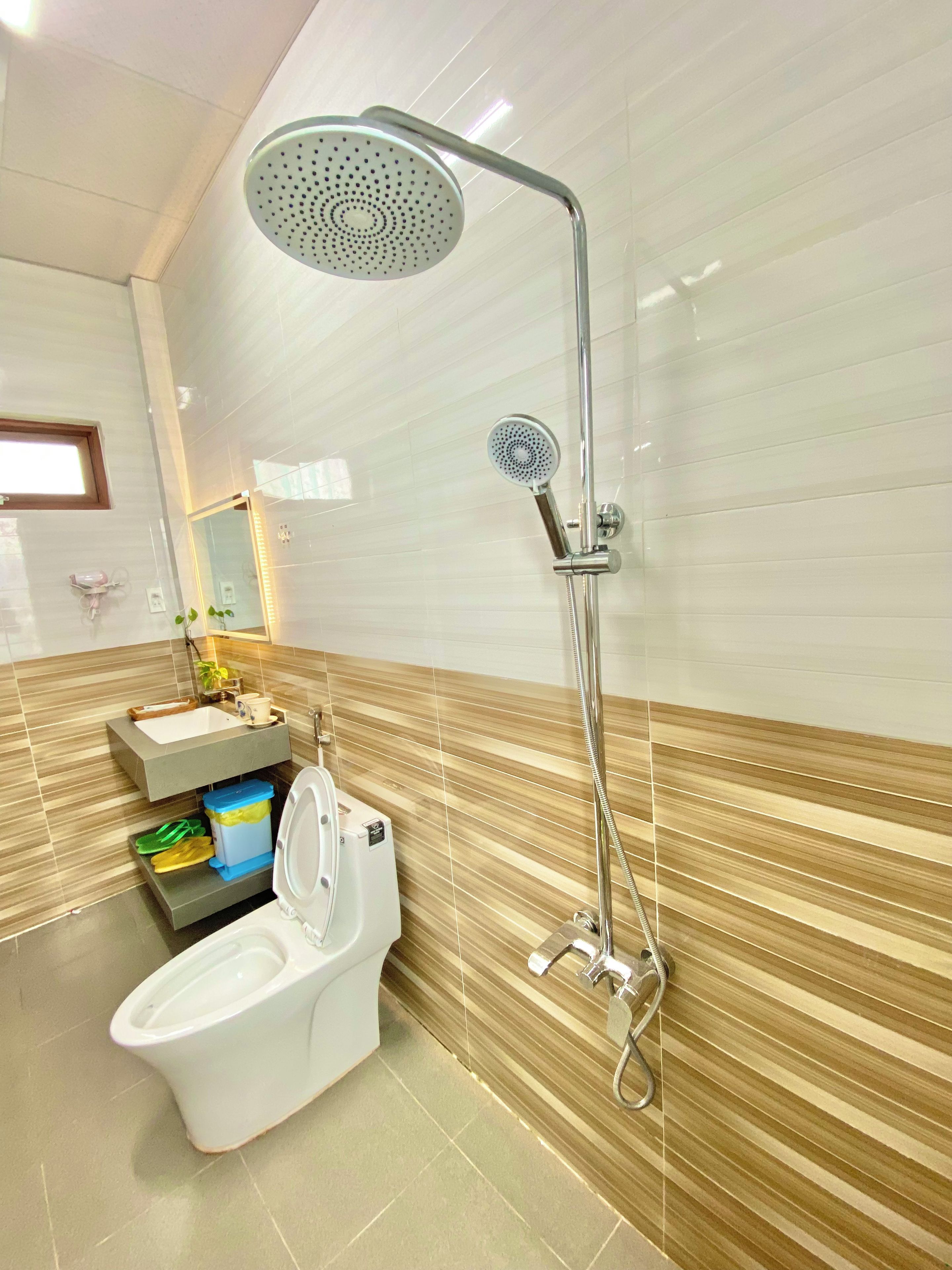 A bathroom with a shower, toilet, sink, and a mirror.