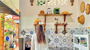 Una cucina con una persona in piedi al bancone, un cartello con la scritta 'Welcome' e diversi oggetti da cucina sugli scaffali.