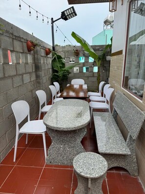 An outdoor patio with a round table and chairs, a bench, and potted plants. - Sea-breeze homestay (Phu Thuy)