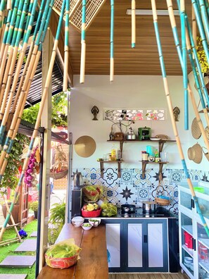 A kitchen with a stove, shelves, and hanging baskets. - Sea-breeze homestay (Phu Thuy)