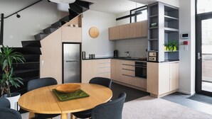 A modern kitchen with a central island, a built-in stove, and a black staircase. - Deluxe Inner-city Apartment on Moray (Dunedin)